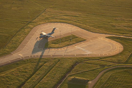Aerial view of a military transport aircraft parked on a paved apron at Travis Air Force Base surrounded by grassy fields during golden hour in Fairfield, California, United States.