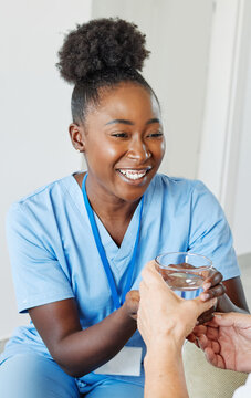 Doctor or nurse caregiver serving a glass of waterl to senior man at home or nursing home