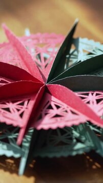 Vertical video: Panning macro lens revealing paper rosette on wood tabletop to show pattern details