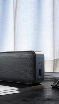 Vertical video: Camera zooming on speaker on desk by window as curtain billowing