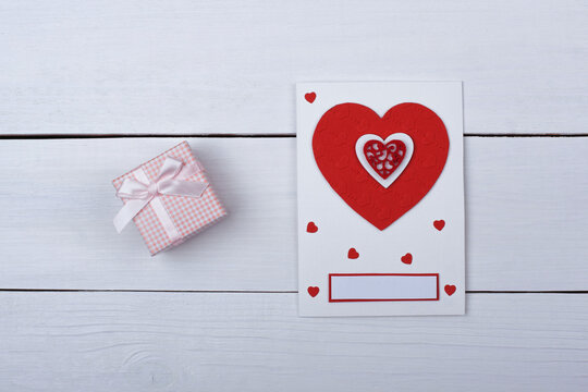 A gift and a card with red hearts on the table.