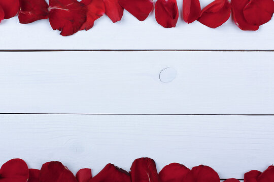 Rose petals on white wooden table.