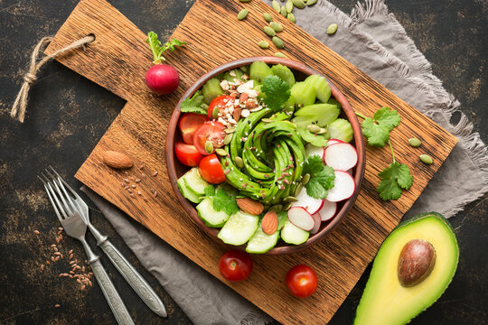 Bowl with diet vegetarian salad from fresh vegetables, top view, dark rustic background