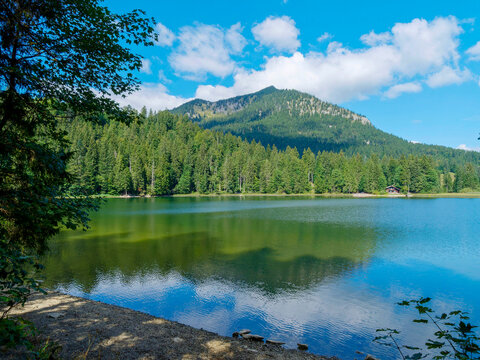 Spitzingsee in Bavaria. Small beach bordering the lakeside walking path with views of the Brecherspitz and Firstgraben peaks and the peninsula on the north shore