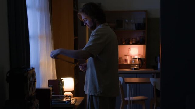 Young adult Caucasian man taking vinyl record from sleeve and playing music on turntable at home. Footage suits lifestyle branding, audio advertising, or mental wellness projects