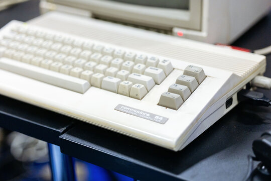 Cologne, Germany - August 26, 2026: Vintage Commodore 64 computer keyboard on a black table with a retro monitor in the background at a gaming exhibition