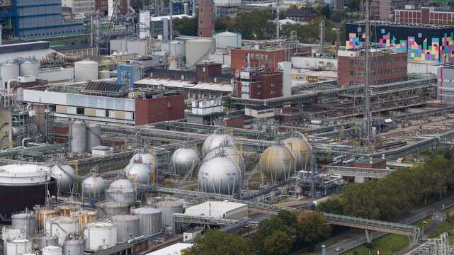 Aerial view of the Bayerwerk chemical plant in Dormagen, featuring large spherical storage tanks, industrial piping, and brick factory buildings in Koln, Nordrhein-Westfalen, Germany.