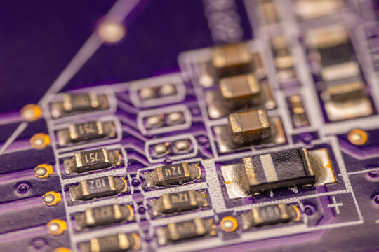 Close-up view of a purple printed circuit board featuring various electronic components including resistors, capacitors, and integrated circuits for technology applications