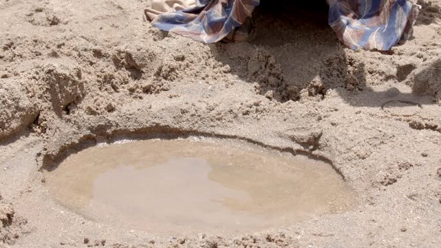 Hands of a girl gathering water from a hole dug in a dry riverbed in Ethiopia.