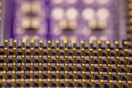 Close-up view of a complex electronic circuit board featuring intricate patterns of metallic pins and connectors against a blurred background of circuit elements