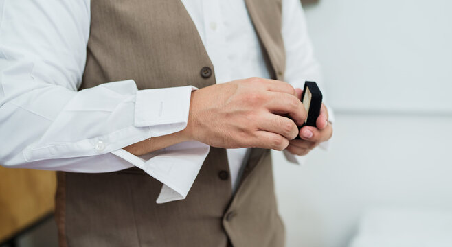 Hombre elegante ajustando gemelos de camisa blanca con chaleco beige para boda o evento formal