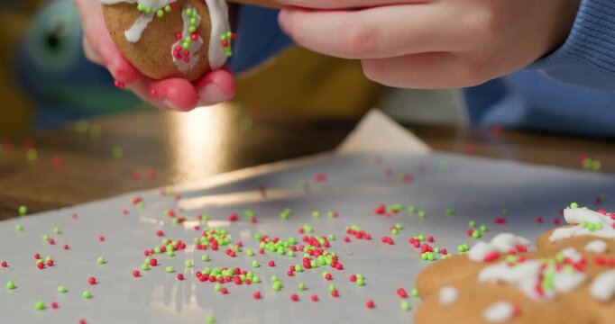 A close-up shot of a boy decorating gingerbread cookies on the kitchen table, preparing a sweet treat for Christmas.
