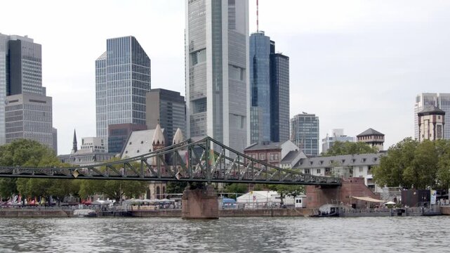 Tilt shot of pedestrians walking across the Eiserner Steg footbridge over the Main River in downtown Frankfurt, Germany.