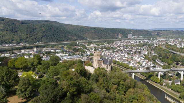 Aerial view of Burg Lahneck perched on a hill above the town of Lahnstein, featuring historic architecture, surrounding forests, a river, and a bridge in Lahnstein, Rheinland-Pfalz, Germany.