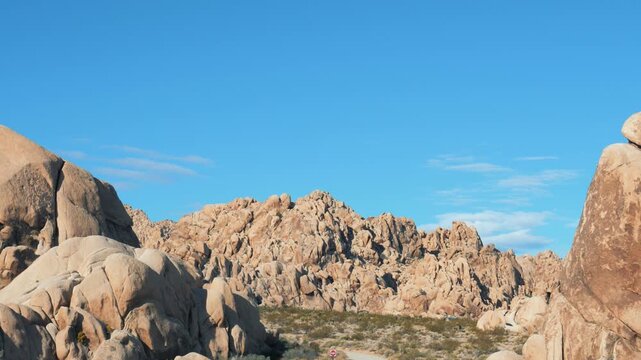 Rock formations standing against a clear blue sky in the arid desert landscape of joshua tree national park, california. Serene and timeless natural panorama.