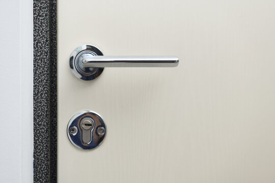 Chrome handle and cylinder lock on a modern entrance door.