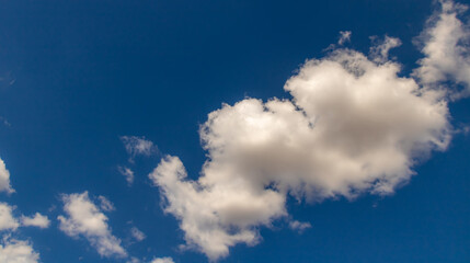 White cumulus clouds drifting across deep blue sky with large copy space in atmospheric summer scene © Miroslav