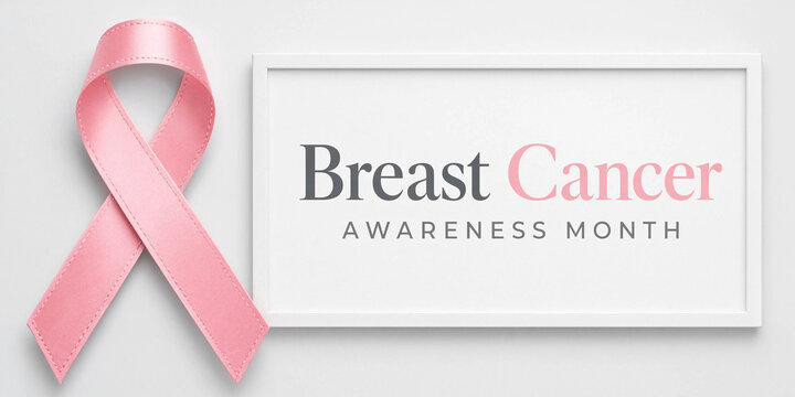 A satin pink ribbon symbol of breast cancer awareness month placed next to a white picture frame on a light background
