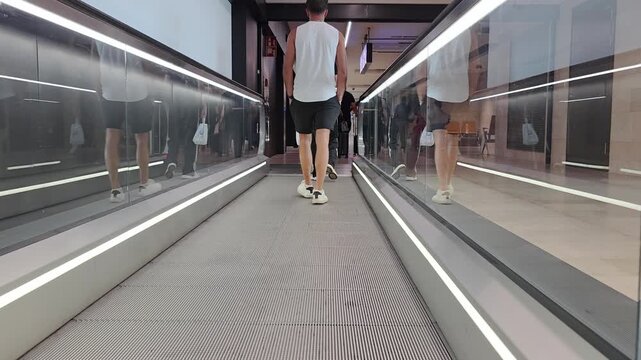 A pedestrianA pedestrian overtakes on the moving walkway in the airport arrivals corridor, travel transit scene, airport terminal move overtakes on the moving walkway in the airport arrivals corridor.