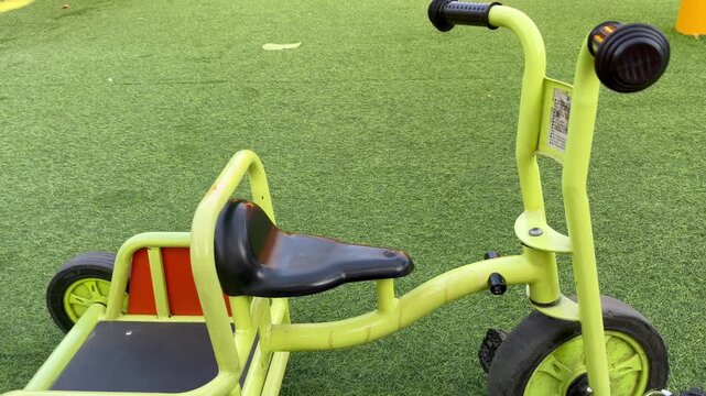 Yellow children tricycle on artificial green grass