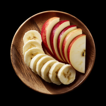 Whole and sliced apple and banana served on round wooden plate, isolated on black background with clipping path