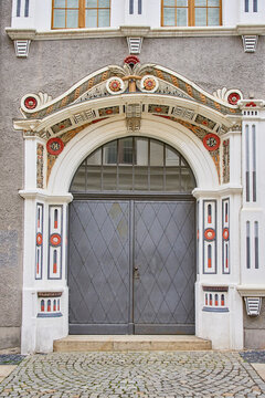 Large gray metal door set in ornate arched entrance with painted decorative details