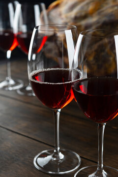 Red wine in crystal glasses. Sliced ham on dark wood. Gourmet pairing. Dark moody background. Spanish delicacy