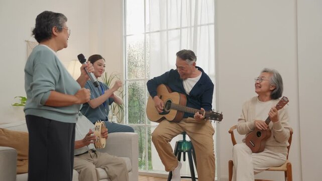 Senior retirement lifestyle elderly people singing music and playing guitar ukulele in bright home living room with joyful expression and friends