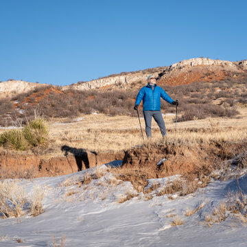 senior male is hiking with trekking poles