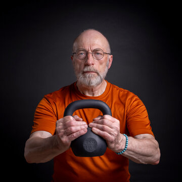 athletic senior man is training with a small iron kettlebell, fitness over 60 and 70 concept