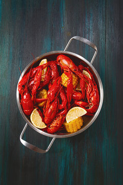 Crawfish boil with corn and lemon served in a metal pot on a wooden table