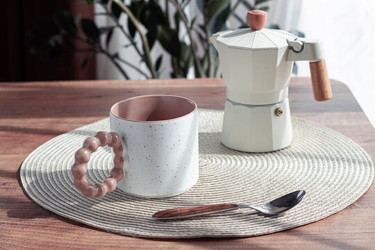 Making morning coffee, geyser coffee maker and mug, on a wooden table, natural light, no people,