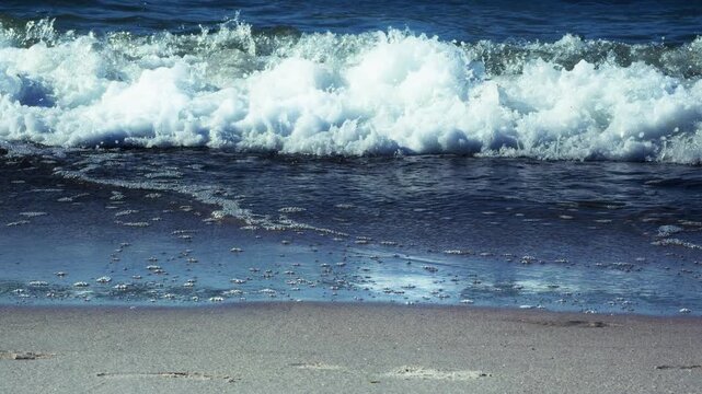 Ocean waves crashing sandy beach white foam sea water nature. Dynamic coastal scene capturing rolling tides and natural water movement along shoreline
