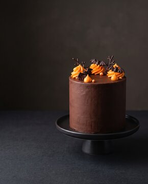 Halloween chocolate cake with orange frosting and bat decorations on dark background