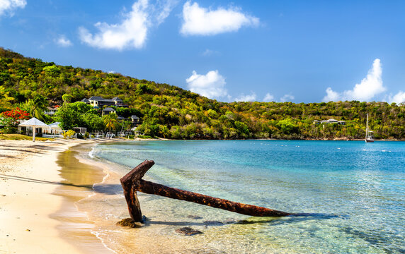 Rusty iron anchor in shallow turquoise water along Galleon Beach in Antigua.