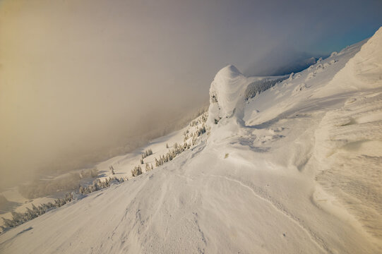 View of Borisov peak covered in deep snow and rime ice under a soft golden light with fog rolling over the slopes Velka Fatra mountains, Zilina Region, Slovakia.