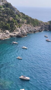 Vertical view of Conca dei Marini bay with anchored boats and Capo di Conca watchtower on the cliff, Amalfi Coast, Italy.
