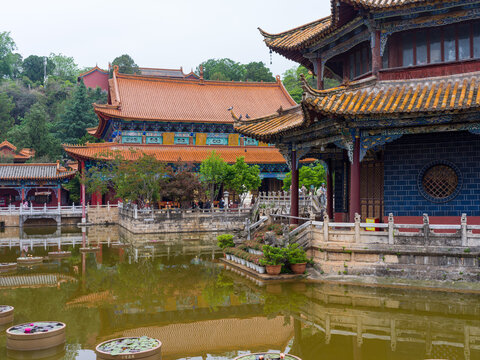 Panoramic view of Chinese temple complex with main hall and pavilion by pond
