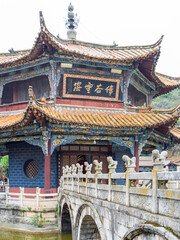 Fototapeta premium Front facade of decorative Chinese pavilion with stone bridge in foreground