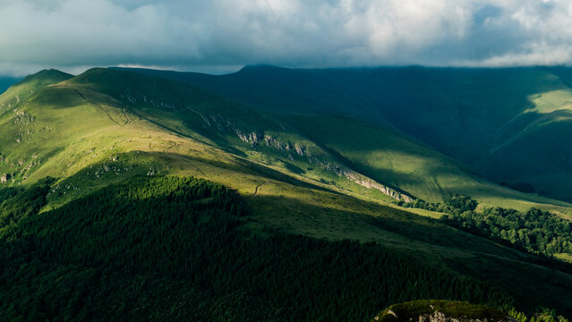 View of Stara planina mountain range with lush green slopes, winding trails, and dramatic shadows cast by clouds in Zaskovci, Pirot District, Serbia.