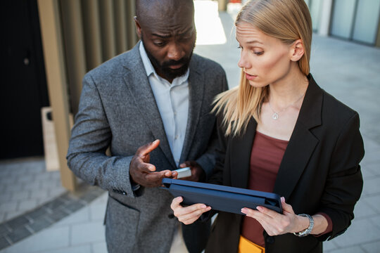 Business colleagues reviewing data on tablet outdoors