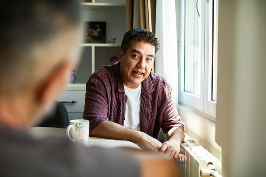 Middle-aged man talking with friend at home