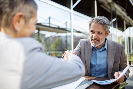 Senior business advisor and client shaking hands outdoors