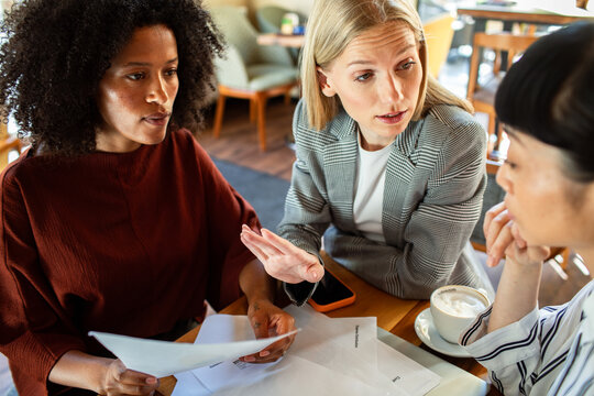 Three businesswomen discussing documents at cafe