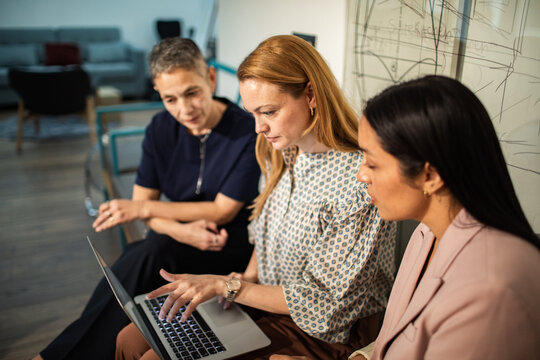Three businesswomen collaborating on laptop in modern office