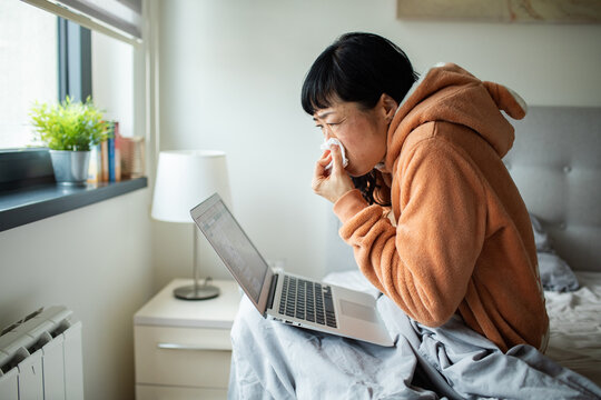 Sick woman working from bed at home