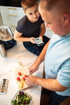 Parent and child preparing healthy lunch in home kitchen
