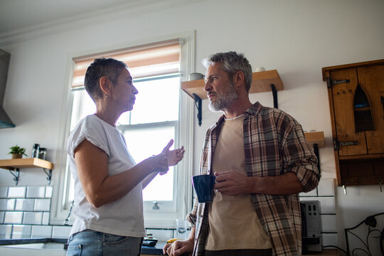 Mature couple discussing over coffee in home kitchen