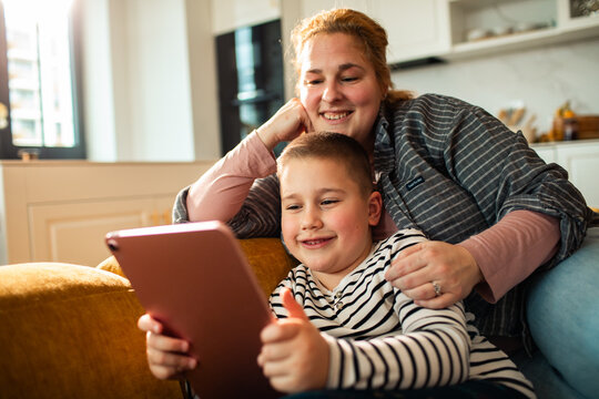 Mother and son using tablet on sofa at home