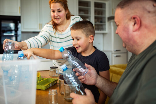 Parents and child recycling plastic bottles at home kitchen